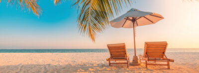 Zwei Liegen am Strand mit Palme.