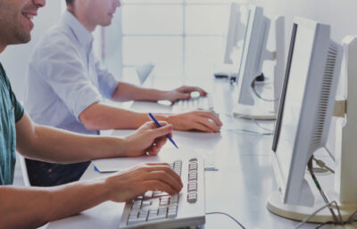 Männer sitzen vor Computern und nehmen an einer Digitalisierungsschulung teil.