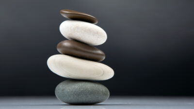 Fünf Steine liegen ausbalanciert auf einander und sind ausgeglichen und im Gleichgewicht.