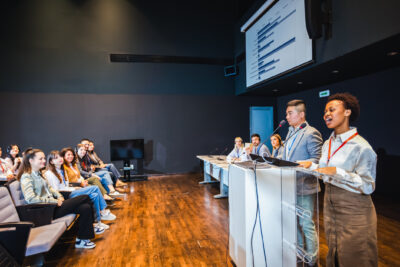 Frau und Mann präsentieren auf einem großen Meeting