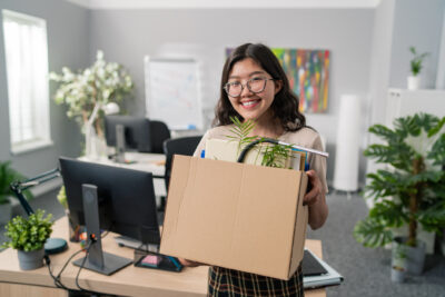 Frau hat gekündigt und verlässt strahlend mit ihren Sachen das Büro